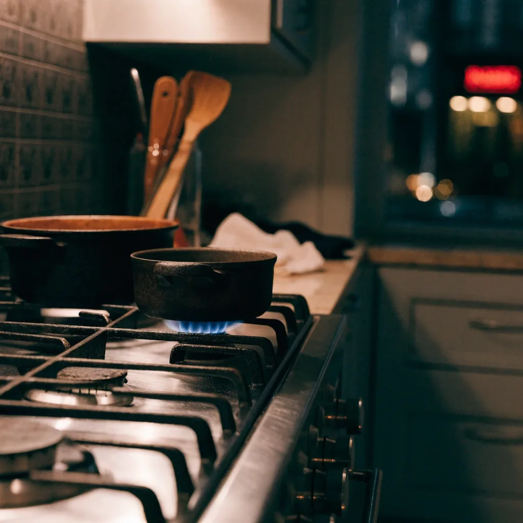 Cocina a gas de cuatro hornallas en una cocina porteña de noche con luz cálida sobre el acero